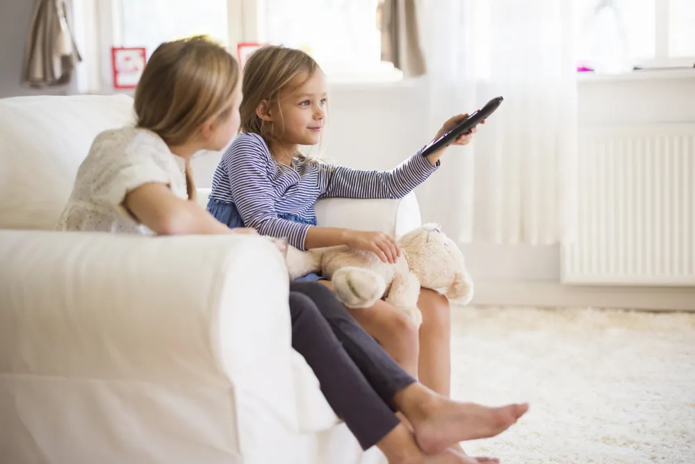 Hand mit einer Fernbedienung vor dem Fernseher